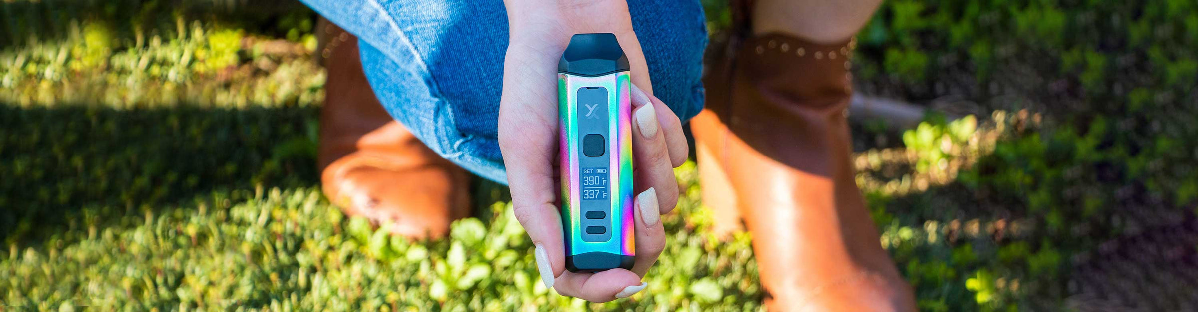 Woman with brown boots holding the Exxus Mini Plus Dual Use Vaporizer outside