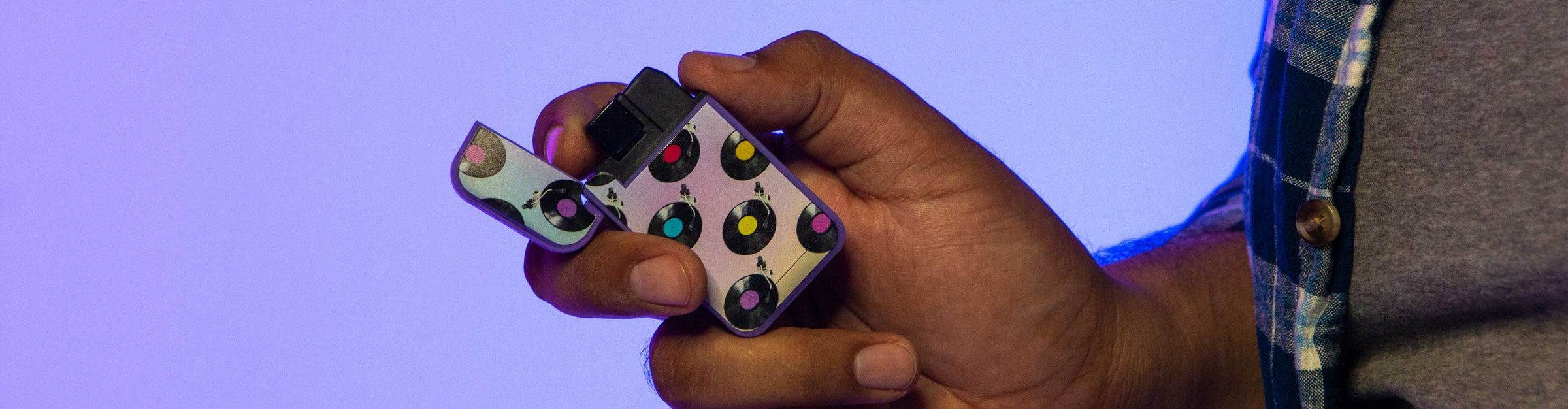 Man in plaid shirt holding Zengaz Lighter inside studio with color lighting